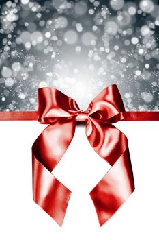 Red gift ribbon bow and silver bokeh isolated on white background
