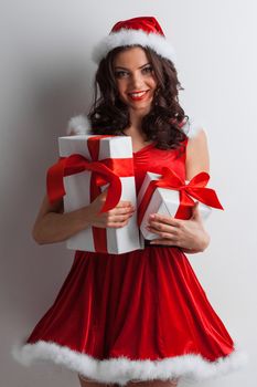 Excited surprised woman in red santa claus outfit holding Christmas presents