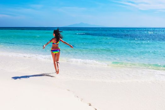 Beautiful happy girl running in tropical sea waves