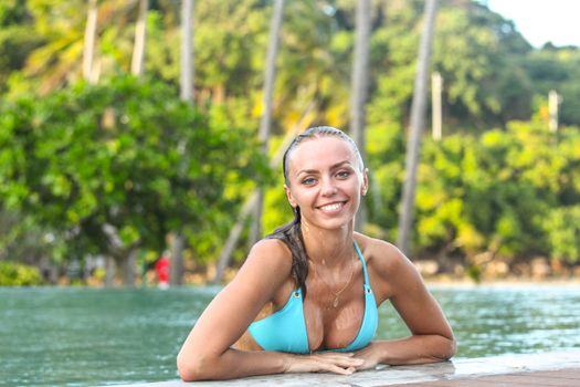 Beautiful sexy woman in bikini relaxing in swimming pool at luxury tropical resort