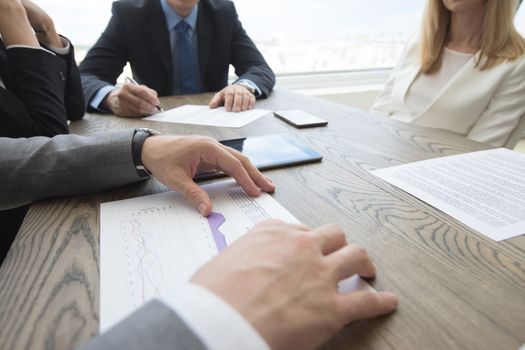 Business people brainstorming at office desk, analyzing financial reports and working with laptops and tablets