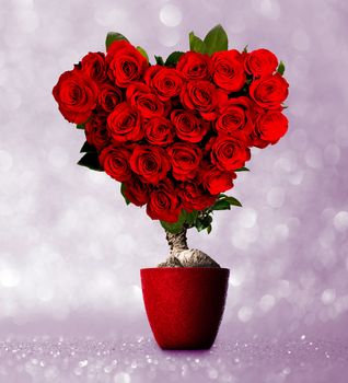 Heart shaped red roses on tree on pink glitter background