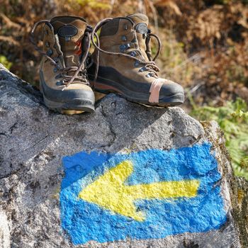 Broken walking shoes on the top of a waymark along the Way of St. James, Spain, Europe