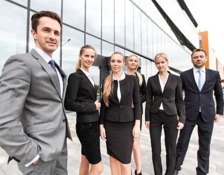 Portrait of successful business people team standing together outdoors near modern office building