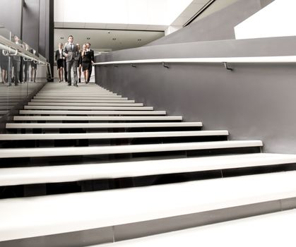 Group of business people walking and taking at stairs in an office building