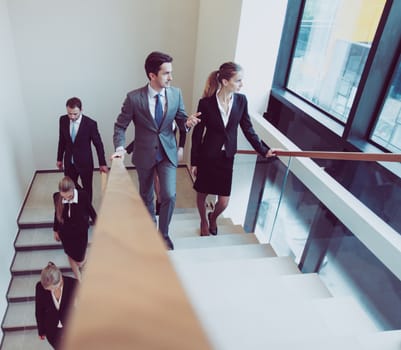 Group of business people walking and taking at stairs in an office building