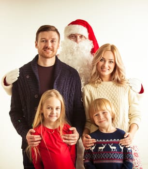 Christmas portrait of happy smiling family with two children ans Santa Claus embracing them