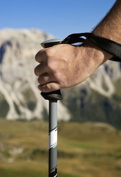 Close-up of a hand with walking pole against mountain in the distance