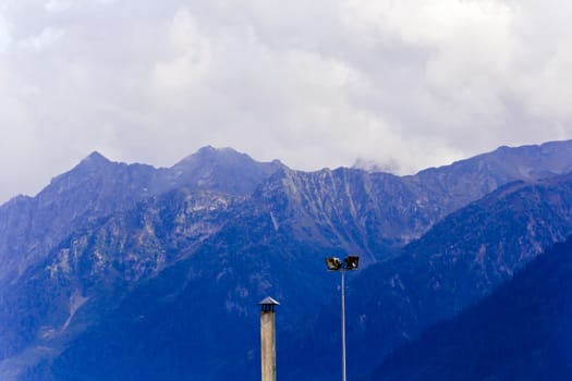 Blue Russian Caucasus mountains landscape with pole wires lights lamps