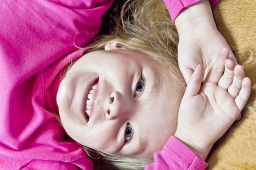 Cute smiling girl with blond hair in pink