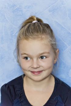 Cute smiling girl with blond hair on blue background