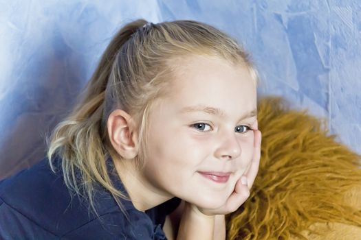 Cute smiling girl with blond hair on blue background