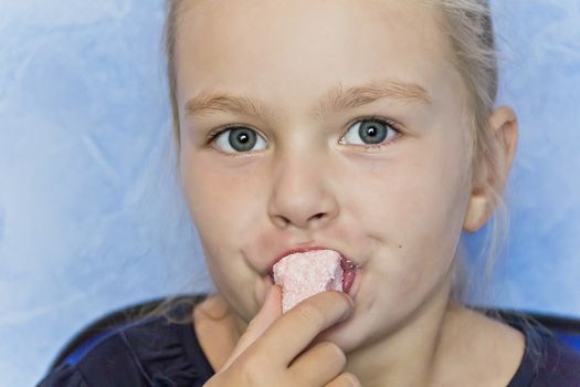 Cute eating girl with blond hair on blue background