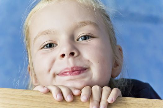 Cute smiling girl with blond hair on blue background