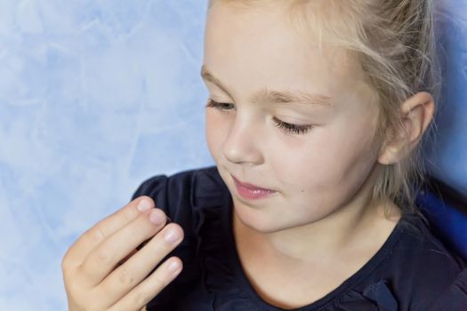 Cute eating girl with blond hair on blue background