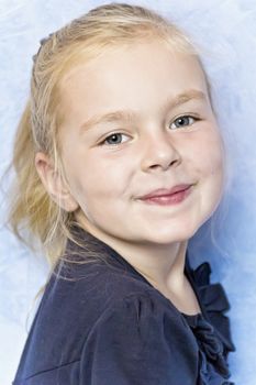 Cute smiling girl with blond hair on blue background