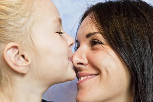 Cute smiling daughter kissing her mother to nose