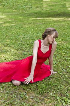 Beautiful lady in red are sittiing on green grass