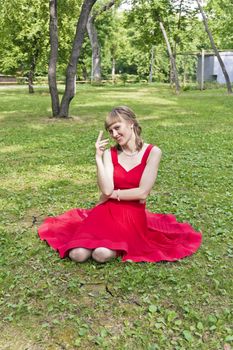 Beautiful lady in red are sittiing on green grass