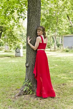 Beautiful lady in red are standing near tree summer day