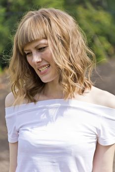 Portrait of talking young woman with blond hair in sunlight