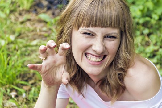 Horizontal portrait of evil woman with blond hair on summer background