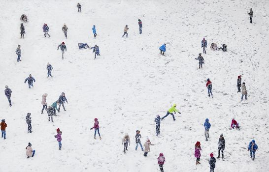 A field during winter, full of playing with the snow children, blurred faces.