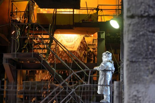 Molten Metal Pouring Out Of Furnace and Workers