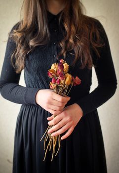 Young girl in black vintage dress and dried flowers