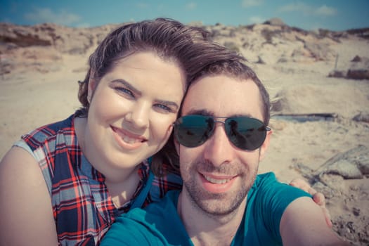 Young couple taking selfie with smartphone or camera at the beach.