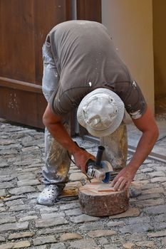 Close up of working man cutting and shaping ceramic tile with angle grinder