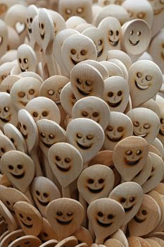 Close up handmade rustic wooden cooking spoons with carved happy smiling face icons in retail market stall display