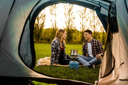 Shot of a happy couple camping on the nature and cooking