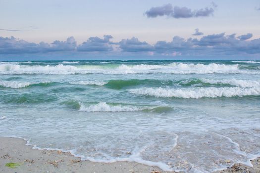Sea coastal waves rolling on empty sandy beach, stormy cloudy sunrise skyview
