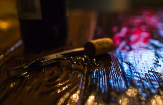 a corkscrew on a wooden table color glow bottle stopper wine