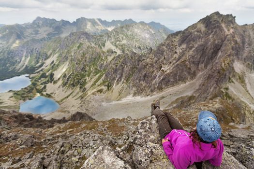 Happy woman with backpack standing and looking on high rocky peaks in Tatra Mountains, Slovakia, Europe
