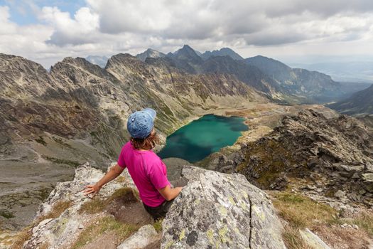 Happy woman with backpack standing and looking on high rocky peaks in Tatra Mountains, Slovakia, Europe