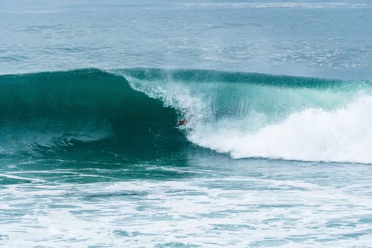 Bodyboarder surfing ocean wave on a sunny day.