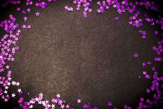 Purple glitter stars on a black background with copy space