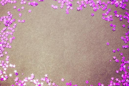 Purple glitter stars on a black background with copy space