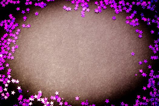 Purple glitter stars on a black background with copy space