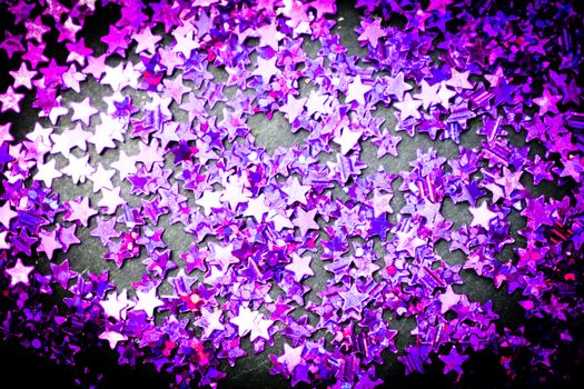 Purple glitter stars on a black background with copy space