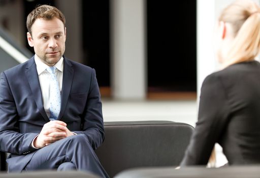 Business people talking sitting on sofa at office lobby, break, interview concept