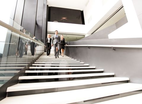 Group of business people walking and taking at stairs in an office building