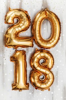 Bright gold balloons figures 2018, New Year Balloons with glitter stars on white wood table background. Christmas and new year celebration