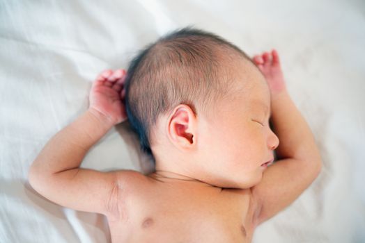 Asian newborn baby boy sleeping in white blanket.