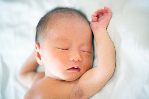 Sleeping Asian newborn baby on a blanket.