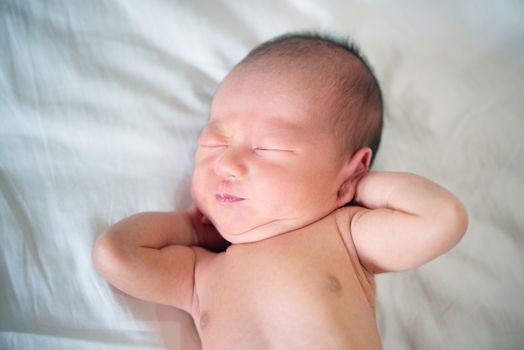 Newborn baby wakes up and stretches, 7 days old.