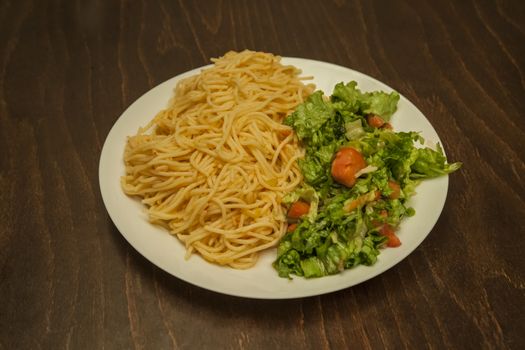 A serving of spaghetti with red sauce and salad.