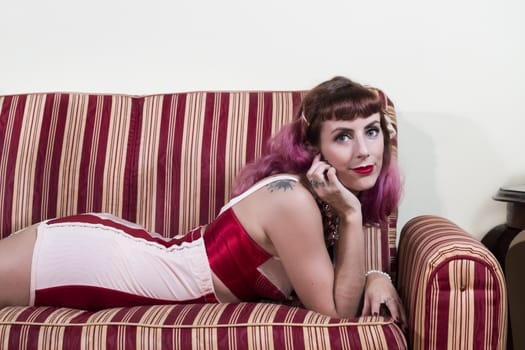 Girl with red vintage lingerie with a striped sofa in the living room.